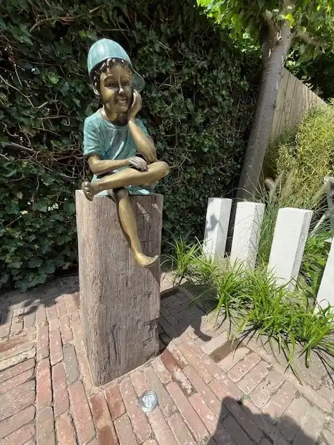 Beeld brons zittende jongen met pet Uitverkoop